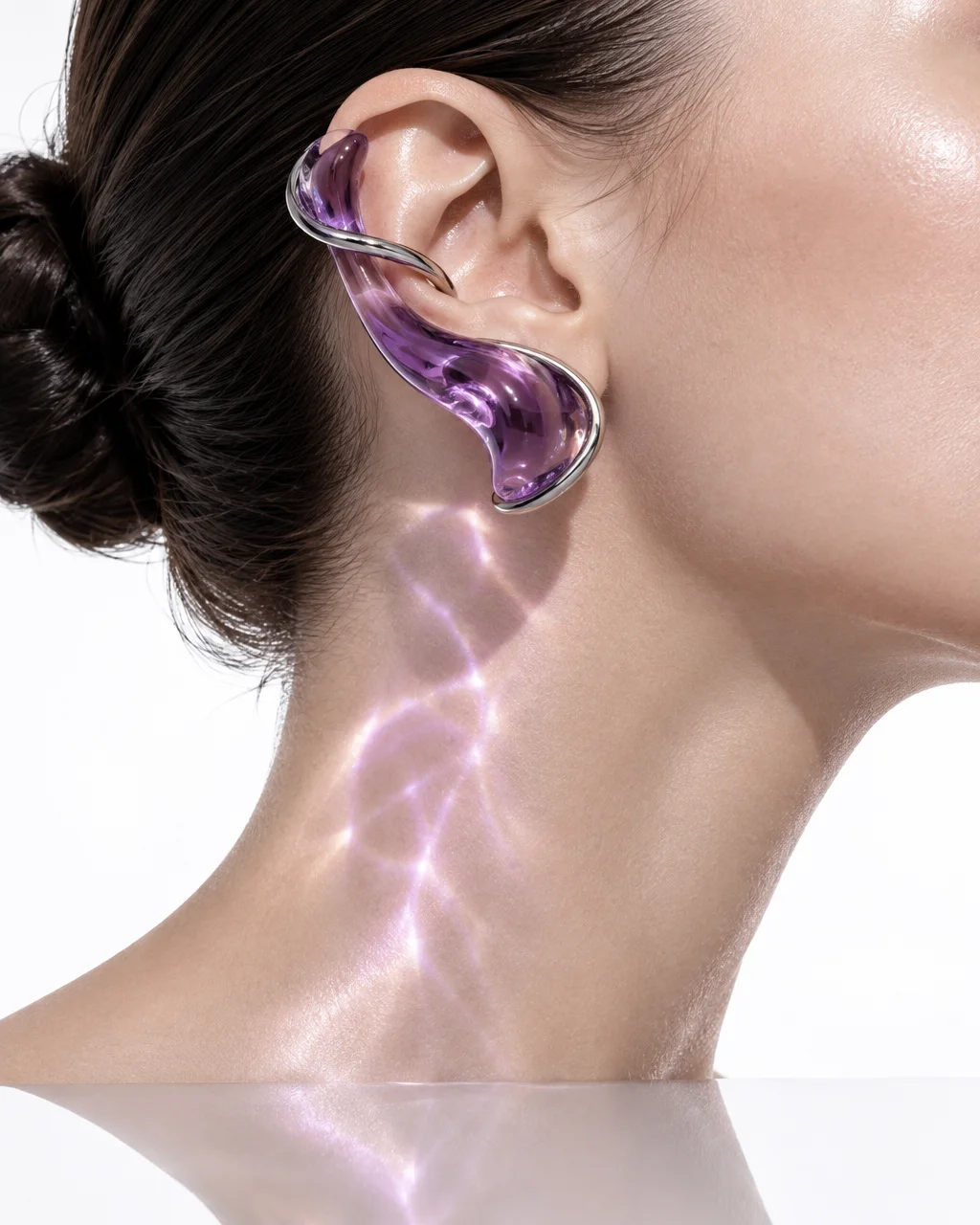 A sculptural purple glass and silver ear cuff casting luminous caustic patterns across a model's neck against a bright studio background.