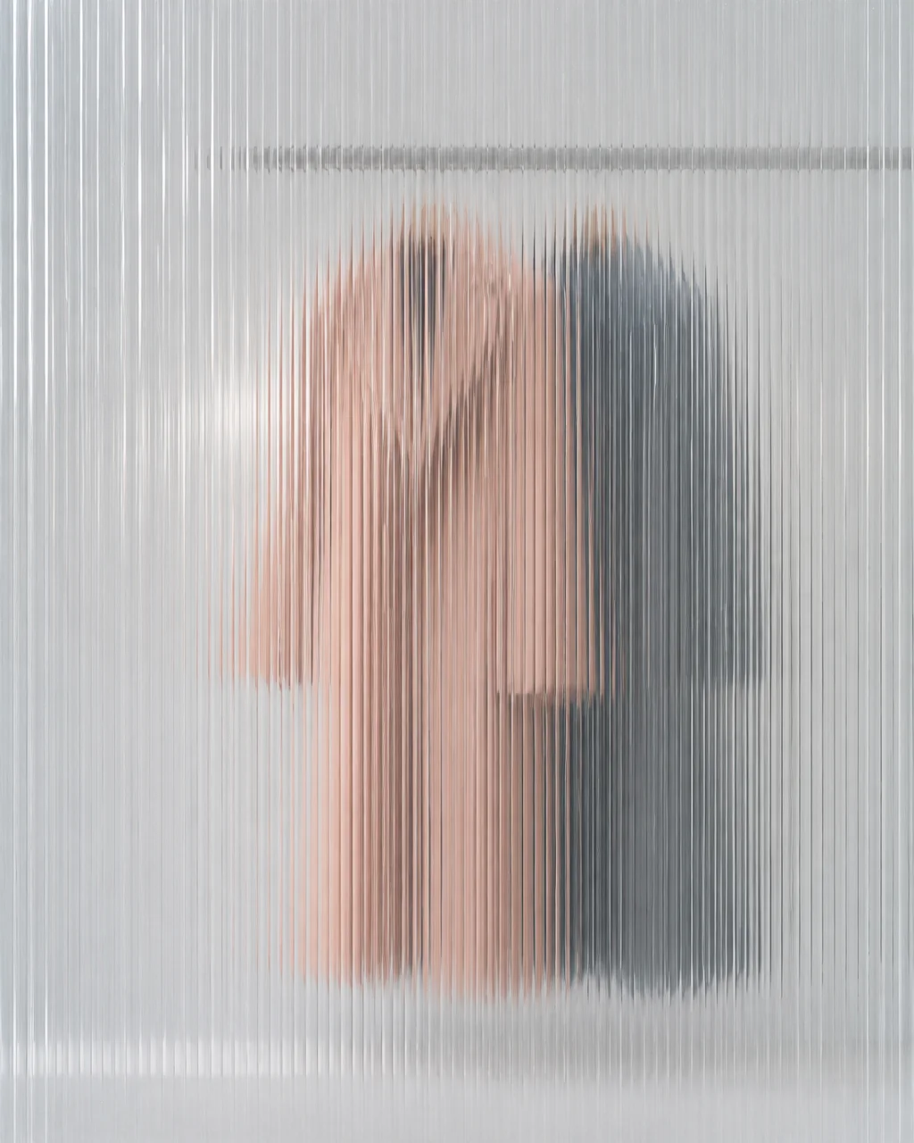 A tailored pink coat and a dark coat hanging on a rack, viewed through translucent ribbed glass.