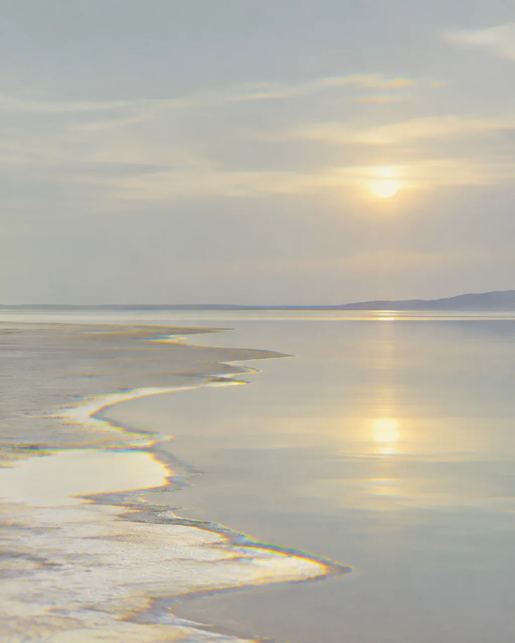 Soft diffused sunlight reflects across still waters and a pale shoreline traced with rainbow chromatic edges.